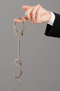 Businessman hand with opened handcuffs over grey background